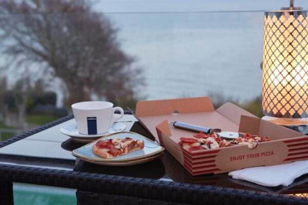 A takeaway pizza and coffee on a sea-view balcony