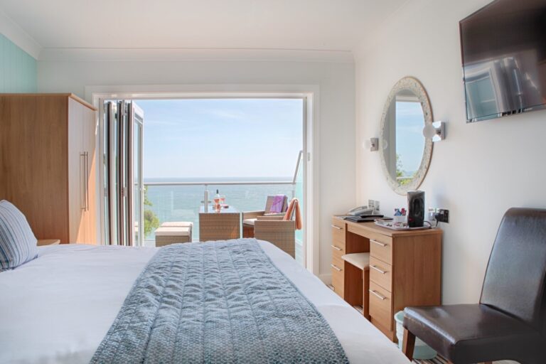 Rooms - Bed and tri-fold balcony doors in a Superior Sea-Facing Room